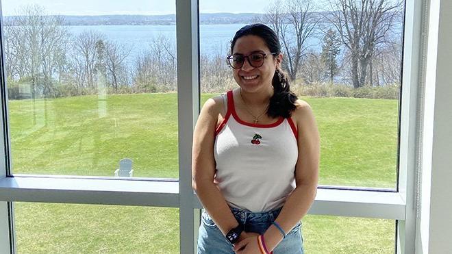 Senior Lucero Blanco stands in front of a window in GHH that looks out to the water